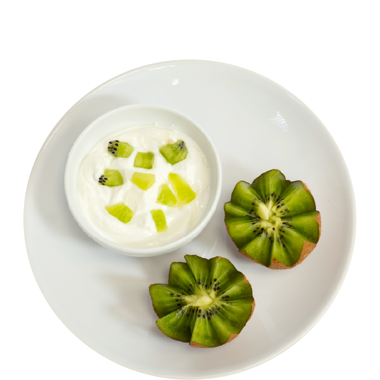 Ein weißer Teller mit einer kleinen Schale Joghurt, der mit Kiwi-Stückchen garniert ist, sowie zwei dekorativ geschnittenen Kiwi-Hälften.